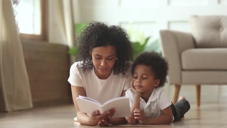 Afrikanischer-Sohn-liegt-auf-dem-Boden-mit-Mutter-lesen-Märchengeschichte