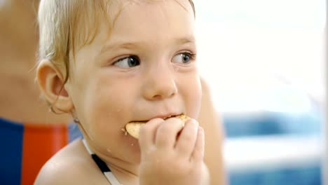 El-niño-come-galletas.-El-niño-después-de-comer-en-la-piscina-come-galletas.