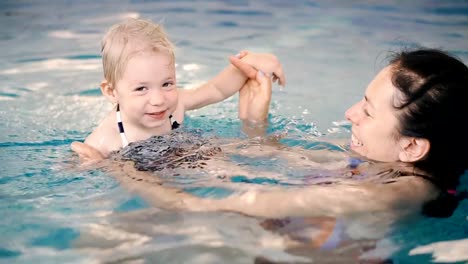 Schwimmbad.-Mama-bringt-einem-kleinen-Kind-das-Schwimmen-im-Pool-bei.