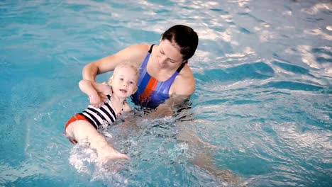 Schwimmbad.-Mama-bringt-einem-kleinen-Kind-das-Schwimmen-im-Pool-bei.