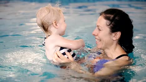 Schwimmbad.-Mama-bringt-einem-kleinen-Kind-das-Schwimmen-im-Pool-bei.