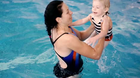 Schwimmbad.-Mama-bringt-einem-kleinen-Kind-das-Schwimmen-im-Pool-bei.