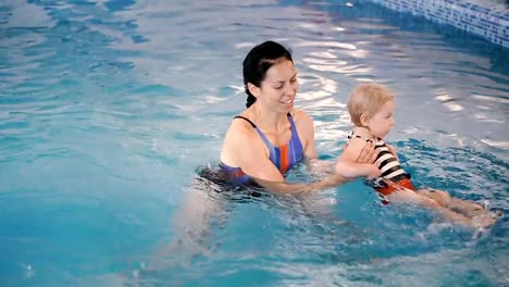 Schwimmbad.-Mama-bringt-einem-kleinen-Kind-das-Schwimmen-im-Pool-bei.