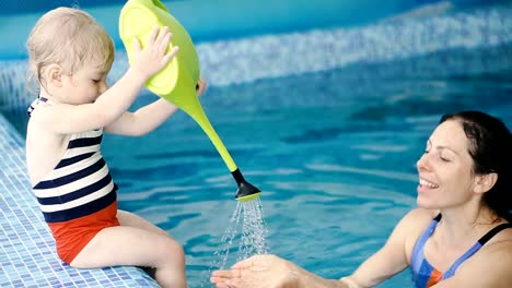 Schwimmbad.-Mama-bringt-einem-kleinen-Kind-das-Schwimmen-im-Pool-bei.