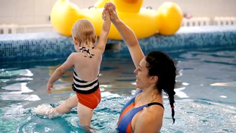 Schwimmbad.-Mama-bringt-einem-kleinen-Kind-das-Schwimmen-im-Pool-bei.