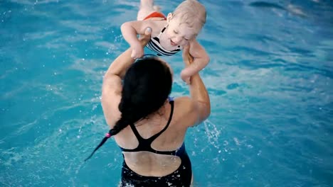 Schwimmbad.-Mama-bringt-einem-kleinen-Kind-das-Schwimmen-im-Pool-bei.