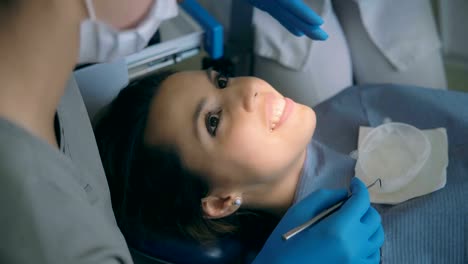 Young-woman-sitting-in-dental-chair-and-talking-with-doctor.-Female-smiling-and-laughing-while-dentist-advising