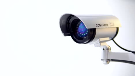 The-surveillance-camera-with-flashing-red-light-on-white-background.-Close-up