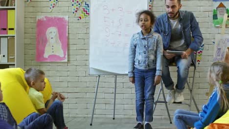 Niña-africana-recitando-un-poema-a-compañeros-de-clase-en-clase