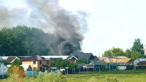 Schwarzer-Rauch-gegossen-hinter-Häusern-im-Dorf