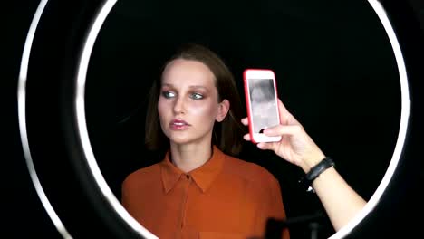 Schönes-Modell-Frau-posieren-für-Smartphone-Kamera-im-Studio.-Sinnliche-Frau-mit-Make-up-Gesicht,-kurze-blonde-Haare-in-Softbox-Licht.-Hinter-den-Kulissen.-Schönheit,-Mode,-aussehen,-make-up,-Kosmetik