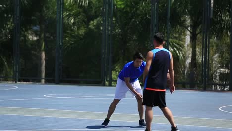 Junge-asiatische-Basketball-Spieler-spielen-auf-Freiplatz