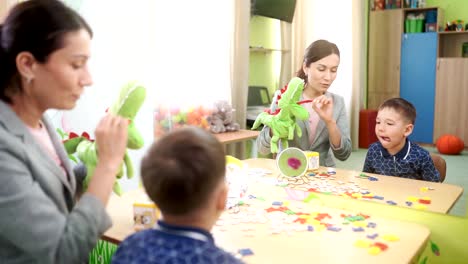 Un-profesor-de-mujer-atractiva-ayuda-a-un-niño-de-preescolar-haciendo-ejercicios-para-la-lengua