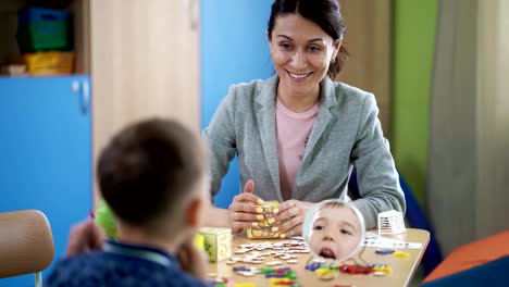 Die-Logopädin-Frau-lehrt-den-jungen-auf-Therapie-Sitzung