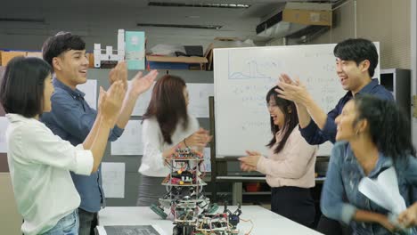 Grupo-de-ingenieros-creativos-exitosos-celebrando-con-su-éxito.-Ingenieros-electrónicos-del-equipo-de-éxito-de-regocijo.