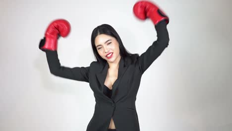 Young-happy-and-energetic-business-woman-keeps-punching-and-raising-hands-with-boxing-gloves-on-white-background