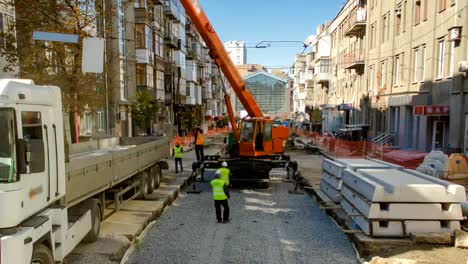 Unloading-concrete-plates-from-truck-by-crane-at-road-construction-site-timelapse