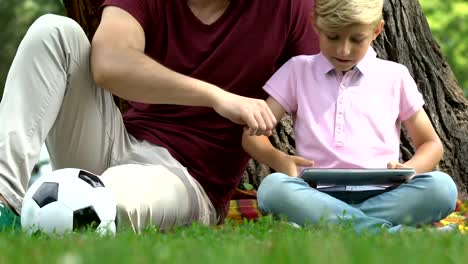 Boy-and-father-playing-computer-game-instead-of-football,-gadget-addiction-issue