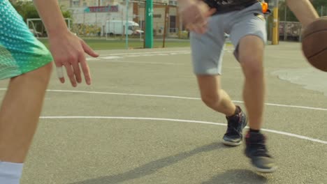 Männliche-Streetball-Spieler-Prellen-des-Balls-auf-Platz