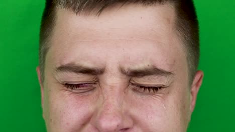 Tears-in-eyes-of-crying-adult-man.-Green-background.-Chromakey