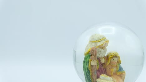 Christmas-nativity-scene-inside-glass-ball-on-white-background.-Left-copy-space.