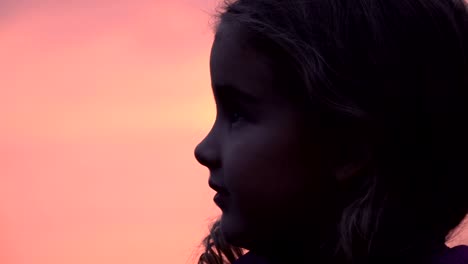 Kid-looking-up-at-the-sky-in-nature.-Little-girl-praying-looking-up-at-purple-sky-with-hope,-close-up.