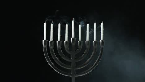 Una-fila-de-nueve-velas-blancas-en-una-menorah-están-soplados-hacia-fuera,-vista-frontal