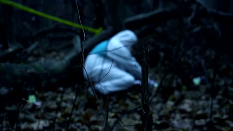 Crime-scene-in-the-woods,-forensic-analyst-working-with-evidence-at-murder-site