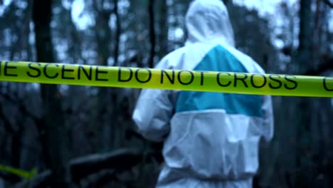 Victim's-clothing-at-crime-scene,-forensic-expert-collecting-evidence-in-forest