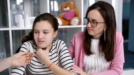 Advice-in-the-doctor's-office.-A-mother-and-daughter-a-teenager-on-the-medical-examination.-A-doctor-examines-a-sore-throat,-the-girl-of-the-patient.