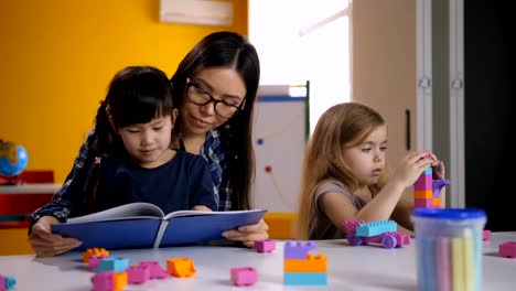 Profesor-y-libro-de-lectura-del-niño-en-el-Kinder