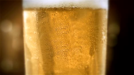 Primer-plano-lenta-luz-fría-cerveza-en-un-vaso-con-agua-cae-sobre-el-fondo-de-la-barra.-Cerveza-artesanal-de-cerca