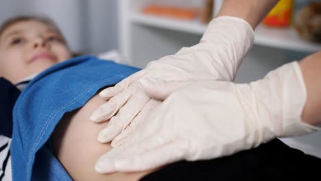 The-doctor-palpated-the-abdomen-of-a-young-patient-in-a-medical-office.,-close-up.