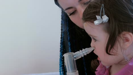 Little-cute-girl-inhaling-through-inhaler-mask-with-her-mom.-Use-nebulizer-and-inhaler-for-the-treatment.