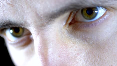 Close-up-of-the-eyes-and-face-of-a-young-man-working-at-a-computer-on-a-Black-Background