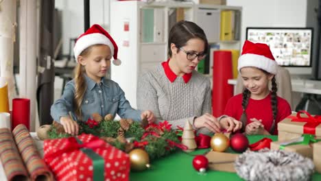 Chicas-haciendo-decoraciones-de-Navidad-con-la-ayuda-de-diseñador-femenino