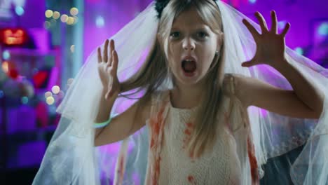 Halloween-Costume-Party:-Little-Girl-in-a-Bloody-White-Bride-Dress-Turns-Around-and-Makes-Scary-Faces.-In-the-Background-Group-of-Monsters-Dancing-and-Having-Fun-in-Decorated-Room-with-Disco-Lights