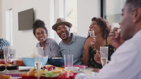 Familia-negra-de-múltiples-generaciones-sentada-en-la-mesa-de-la-cena-celebrando,-de-cerca-de-ángulo-bajo