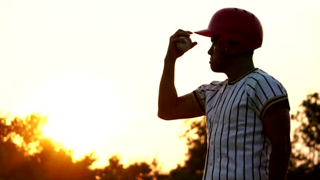 Baseball-Spieler-hält-einen-Baseball-mit-dem-Licht-des-Sonnenuntergangs