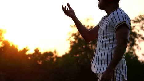 Baseball-Spieler-hält-einen-Baseball-mit-dem-Licht-des-Sonnenuntergangs