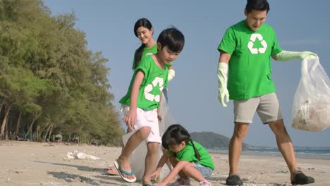 Group-of-volunteers-in-green-t-shirts-cleaning-up-the-beach-with-plastic-bags-full-of-garbage.-Slow-Motion.-Safe-ecology-concept.-4k-resolution.