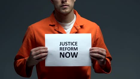 Justice-reform-now-demanding-on-card-in-hands-of-Caucasian-prisoner,-fairness