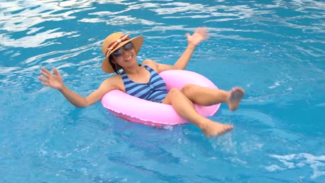 Chica-jugando-y-nadando-en-el-anillo-de-goma-flotando-en-la-piscina