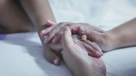 Mother-holding-hand-of-his-son-sick-bed-in-the-hospital.-Touch-the-hand-Slow-motion.-care-encouragement