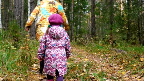 Mutter-und-Tochter-laufen-den-Weg-im-Wald-entlang.