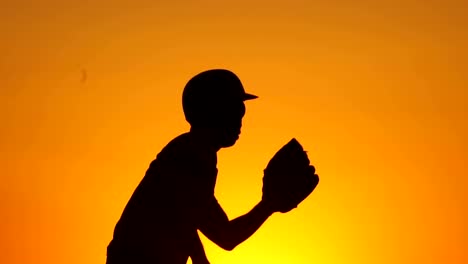 Silhouette-man-with-a-baseball-glove-catching-a-baseball