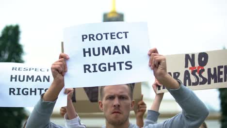 Activists-chanting-human-rights-slogan-holding-banners,-rally-against-harassment