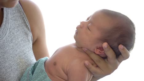 4K-Medium-close-up-of-young-adult-asian-woman-mother-standing-near-window-in-home-bedroom-and-carrying-her-sleeping-newborn-baby-girl-daughter-in-her-hands.-Mother-day-and-baby-health-care-concept.