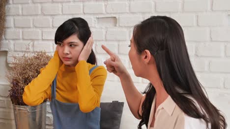 Asian-family-Teenage-daughte-closed-his-ears-with-his-hands-while-her-mother-yells-at-her-at-home.-Family-crisis,-conflict-and-relationships-problems-concept