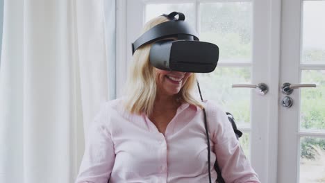 Reife-behinderte-Frau-im-Rollstuhl-zu-Hause-mit-Virtual-Reality-Headset-Gaming-Holding-Controller